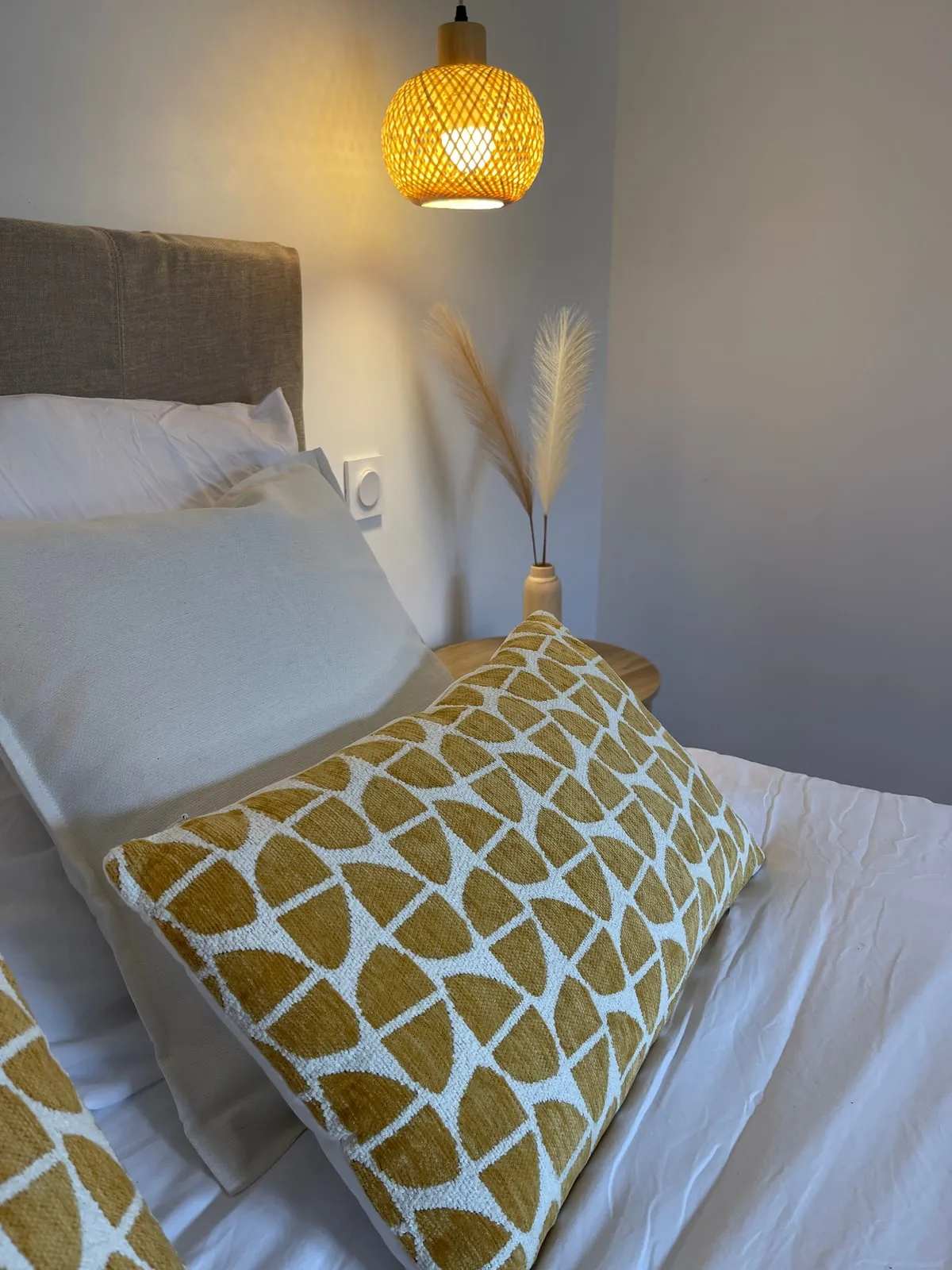 Chambre avec coussin graphique moutarde et suspension en rotin